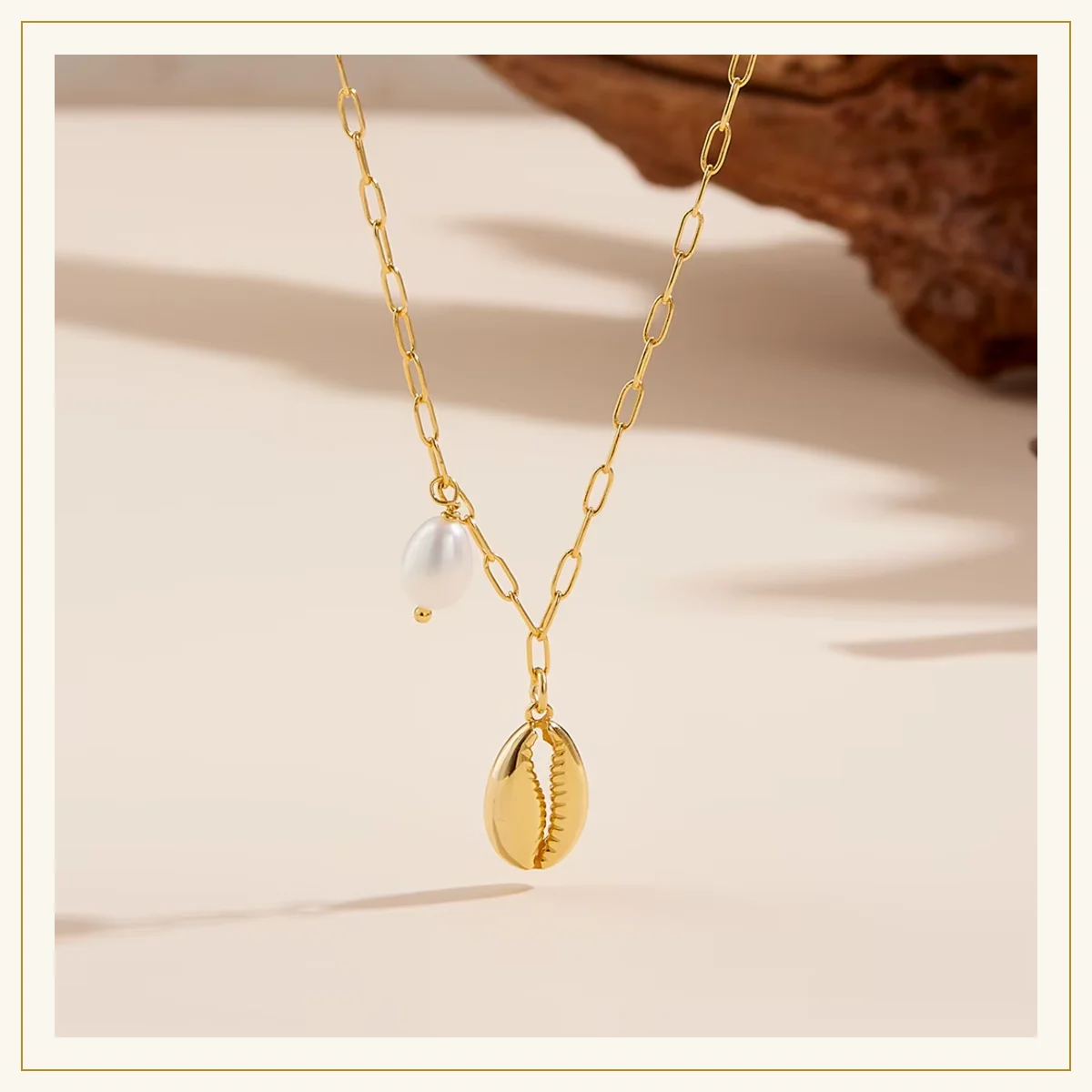 Gold cowrie shell and pearl necklace styled on wood