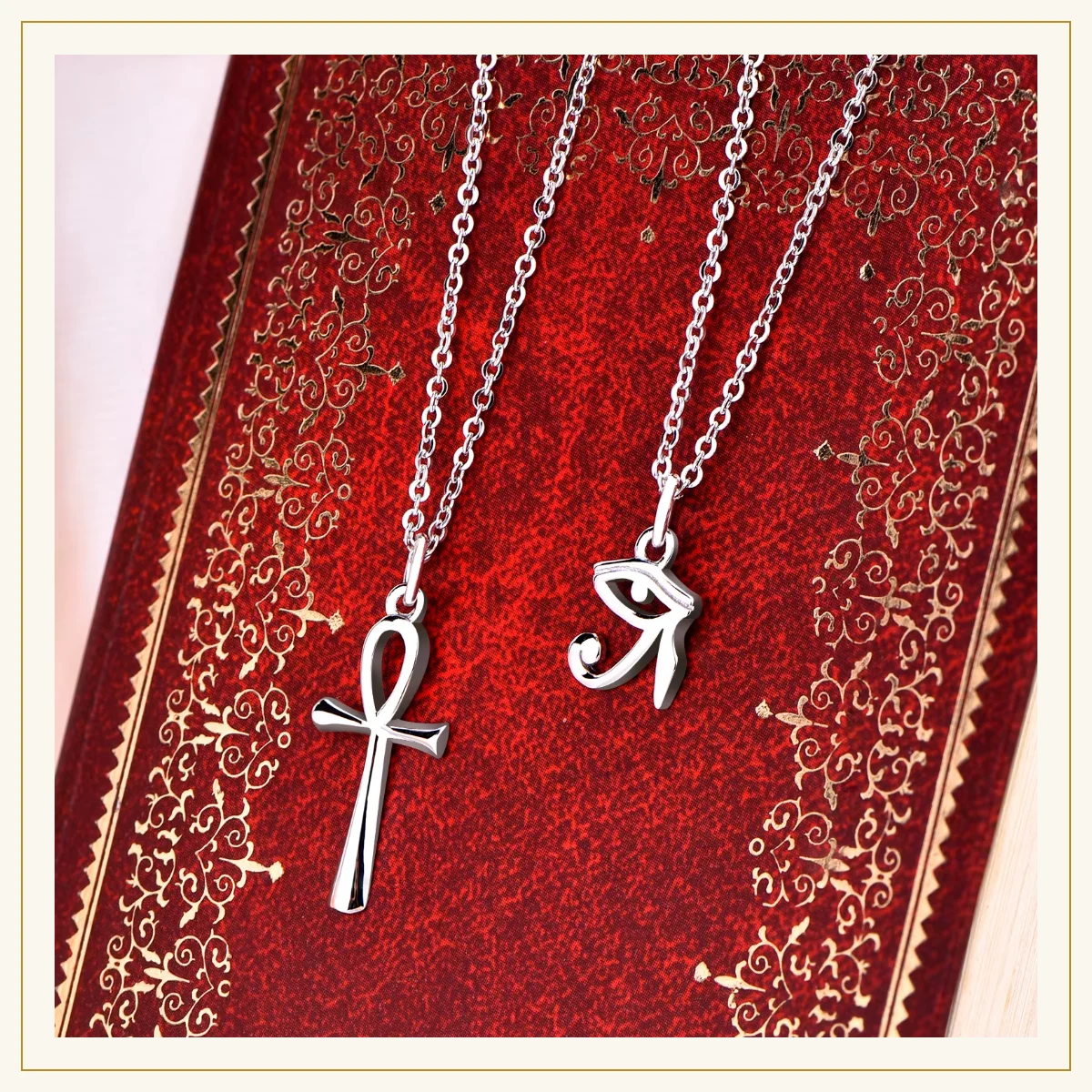 Silver ankh and Eye of Horus pendants on red background